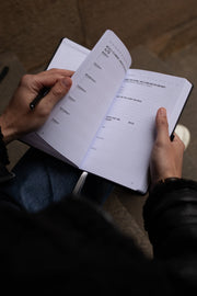 Hands browsing the weekly planning and reflection pages of the Focus Journal