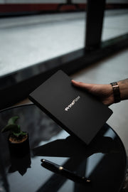 Hand holding a black box with 'PrimeFlow' branding on a reflective surface.